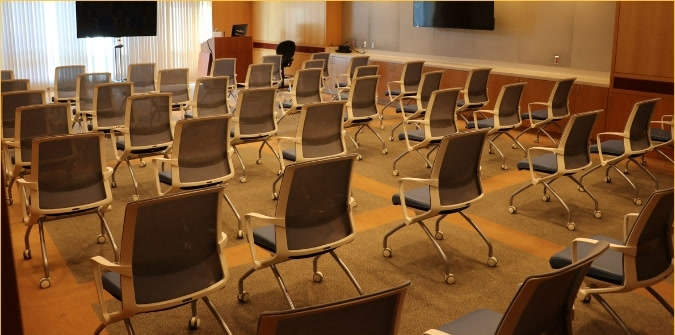Orbach 240 conference room set up theater style, with rows of chairs facing the front of the room and a wall-mounted monitor.