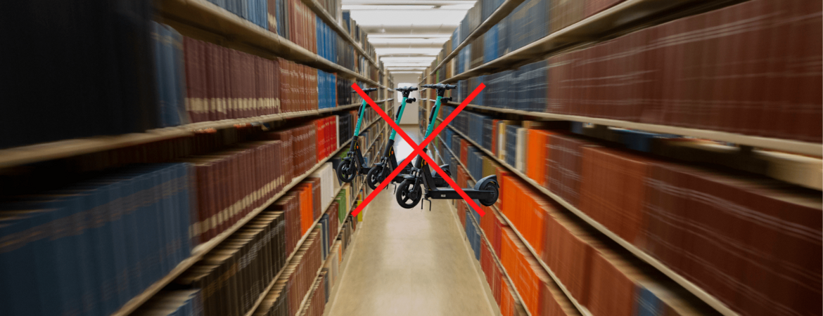 Image of library aisle. Scooters in middle of the aisle with a red x. 