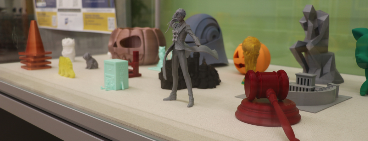 Layer by Layer display case showcasing 3D printed objects. 