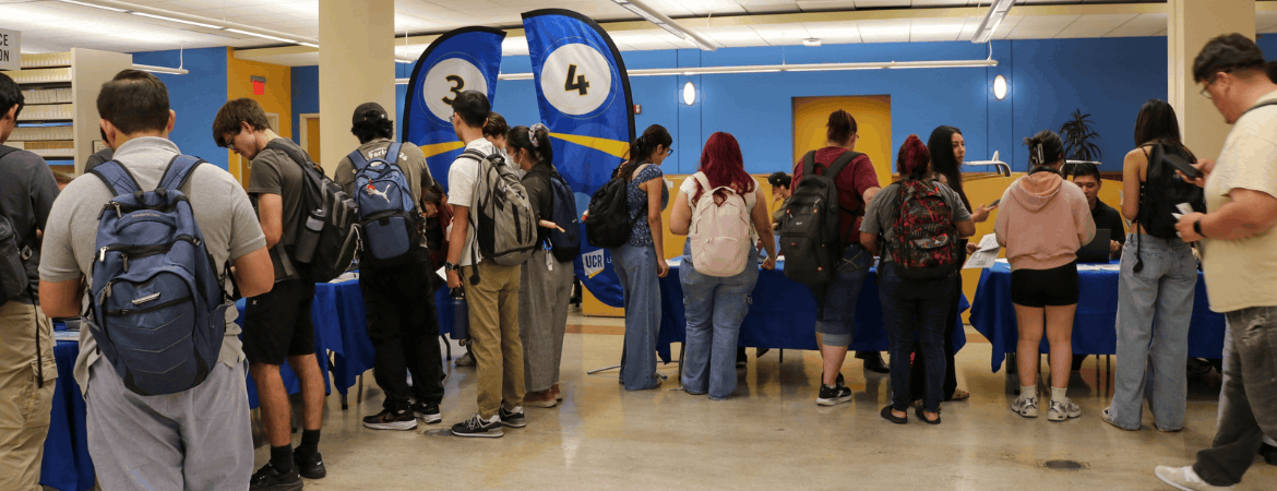 Student attending the 2026 Library Open House in Rivera Library, blur flags in the background indicate stations where students are gathered.