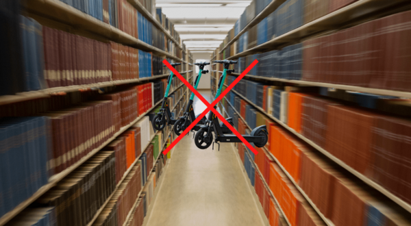 Image of library aisle. Scooters in middle of the aisle with a red x. 