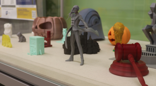 Layer by Layer display case showcasing 3D printed objects. 