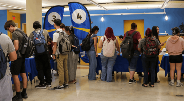 Student attending the 2026 Library Open House in Rivera Library, blur flags in the background indicate stations where students are gathered.