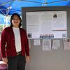 A student poses with their research poster.