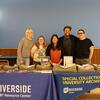 Staff from the UCR Library, UCR LGBT Resource Center, and IE Print & Zine Fest pose for a photo at a pop up exhibit before the zine-making workshop.