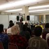 Laila Lalami reads at a podium to a full seated audience in UCR's Tomás Rivera Library Special Collections Reading Room.