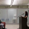 Laila Lalami reads from The Dream Hotel at a podium while two audience members listen in the foreground.